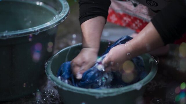 Close Up of Hand Scrubbing Laundry by Hand in Plastic Basin