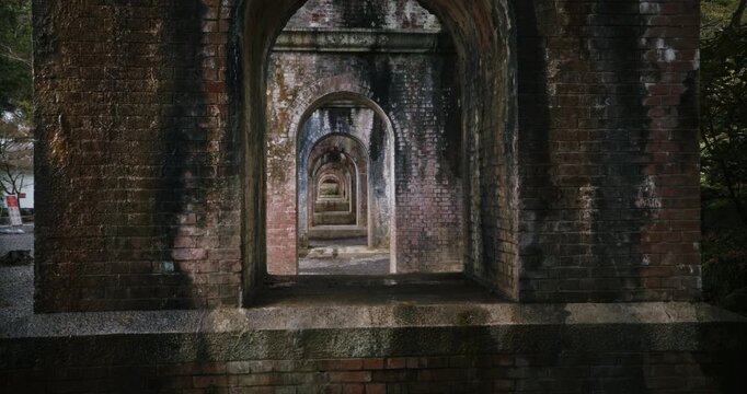 Slow motion view through arches under brick bridge in Japan