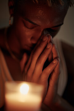 Black nonbinary adult meditating by candlelight in minimalist home. Calm inclusive mental wellness scene. Gender neutral person with candles, mindfulness meditation, mental health, home wellness.