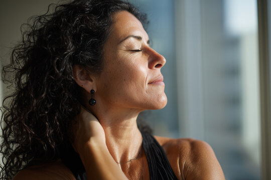 Hispanic professional woman stretching in office wellness room. Realistic work-life balance and stress relief scene.Elderly latin woman, senior neck stretch in office, self care moment, work life bala