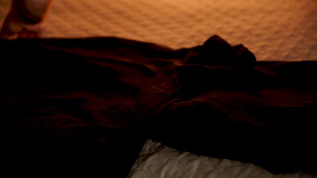 Dark clothing resting on a quilted bedspread under warm evening light