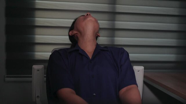 Person with Head Tilted Back: A person sits with their head tilted back, eyes closed, in a moment of deep thought or relaxation. The blinds cast striped shadows across the scene.
