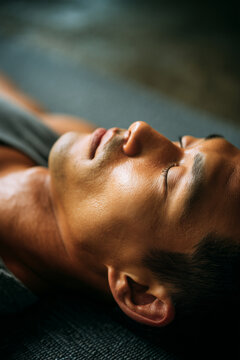 Southeast Asian man practicing guided breathwork therapy in plant-filled holistic wellness studio. Asian man in breathwork therapy, mindfulness therapy session, inclusive wellness, diversity theme.