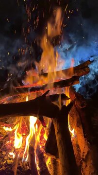 Cinematic wood fire in the dark with illuminated atmospheric smoke, vertical