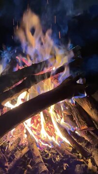 Vertical night campfire with glowing red embers and backlit changing smoke