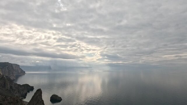 Seascape coastal cliffs dramatic high angle view of rocky coastline and calm sea under cloudy sky with crepuscular rays
