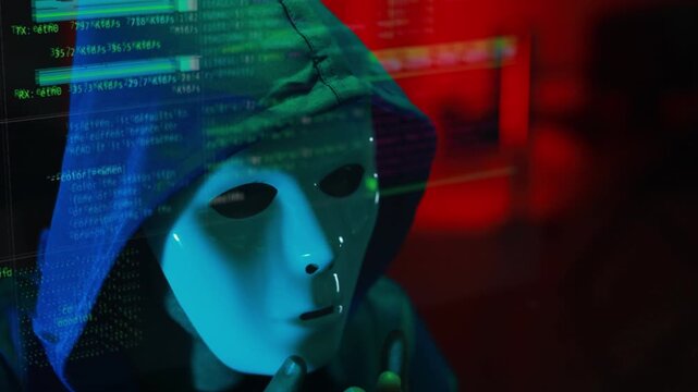 Masked hacker hacking computer. anonymous hacker wearing mask and black hoodie in dark room. online scam and cyber security threat.