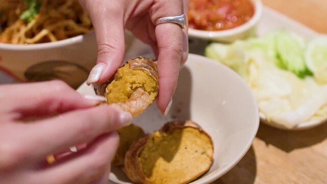 Person Dipping Crispy Pork Skin into Grilled Crab Paste in Bangkok