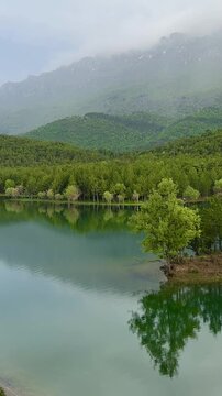 Clear mountain lake reflecting the surrounding forest and sky