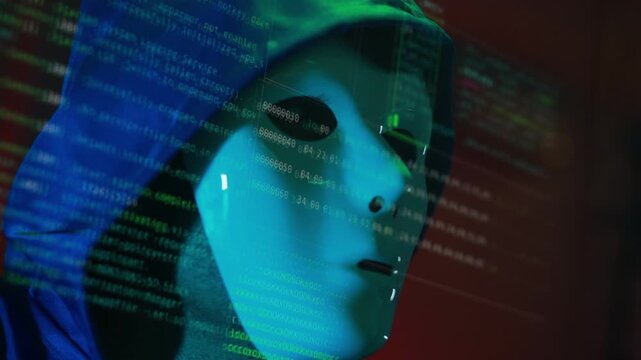 Masked hacker hacking computer. anonymous hacker wearing mask and black hoodie in dark room. online scam and cyber security threat.
