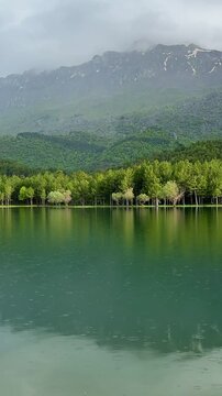 Calm water reflecting scenic mountain range and clear blue sky