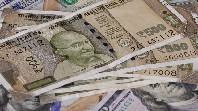 500 Indian rupee notes falling on one hundred US dollar banknotes. Concept of exchange rate, global finance, investment and international economy. Real time video footage.