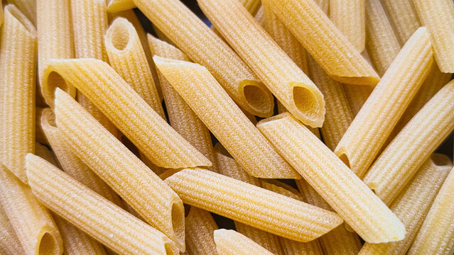 uncooked pasta penne rigate texture closeup view abstract wheat staple food background