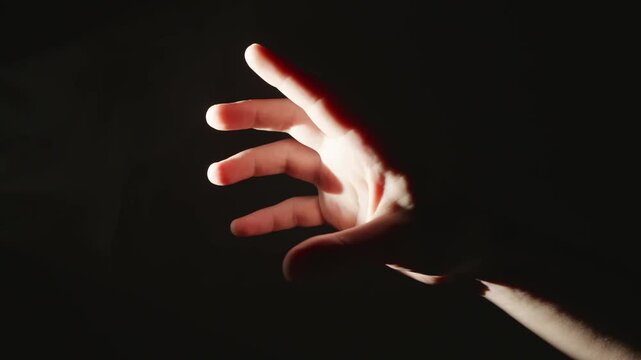 Hand reaching from shadow into warm light beam horizontally