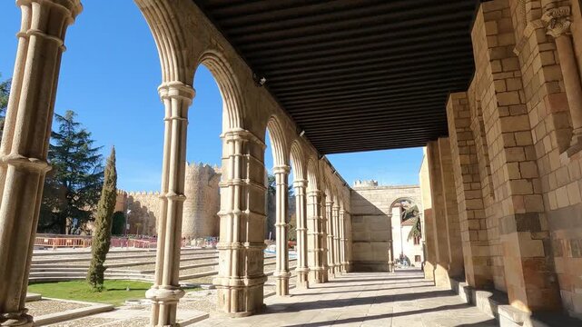 Caminando bajo el soportal y arcada de la bas&iacute;lica rom&aacute;nica de los santos Vicente, Sabina y Tristera en Avila, Espa&ntilde;a