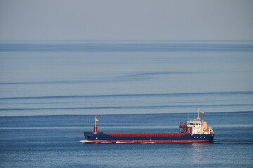 Fototapeta premium Cargo ship traveling on calm blue ocean
