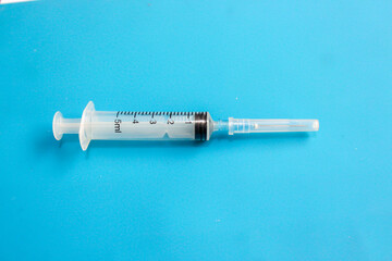 Disposable Medical Syringe on Blue Background with Copy Space