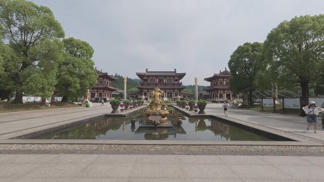 4K static shot of people walking near the grand traditional Chinese temple pavilion and reflection pond, shot in ProRes Log format.