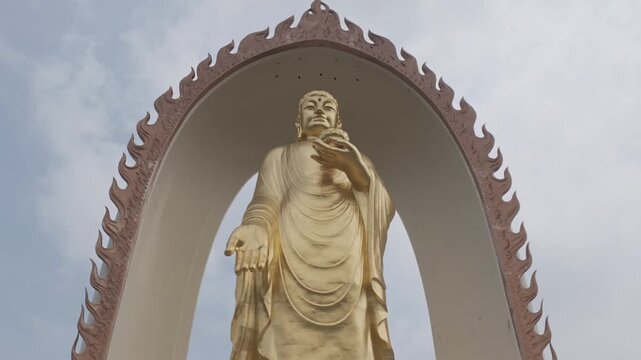 4K resolution cinematic medium shot of the giant golden Amitabha Buddha statue standing inside a flame-shaped architectural arch at Donglin Temple in Jiujiang, China, shot in ProRes Log.