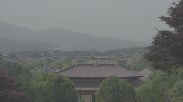 4K resolution pan right cinematic shot of a grand traditional Buddhist temple complex surrounded by dense green forests and misty mountains in Jiujiang, shot in ProRes Log format.