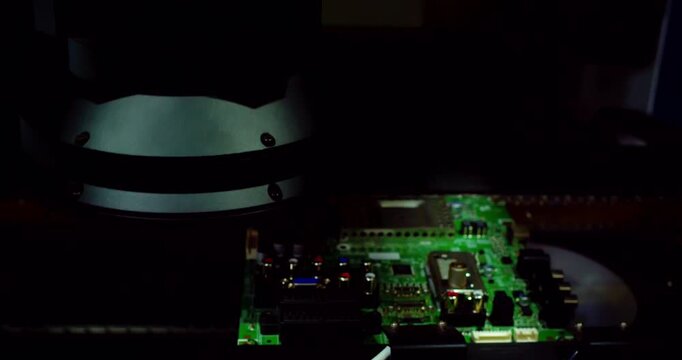 Cinematic footage of an advanced printed circuit board moving through an automated factory line. Vibrant strobe lights illuminate microchips as the hardware undergoes high-speed optical inspection.