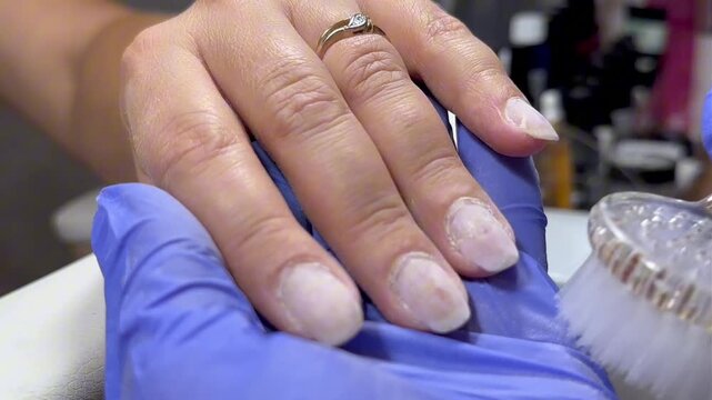 Gloved hands work carefully on a nail. Tool glides gently over nail surface. Precision and care define the process. Perfect for beauty or wellness content
