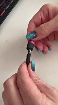 Close-up hands hold a disassembled cable. Fingers with blue glitter nails grip the exposed wires. Ring glints on one finger. Viewer sees cable's inner structure clearly