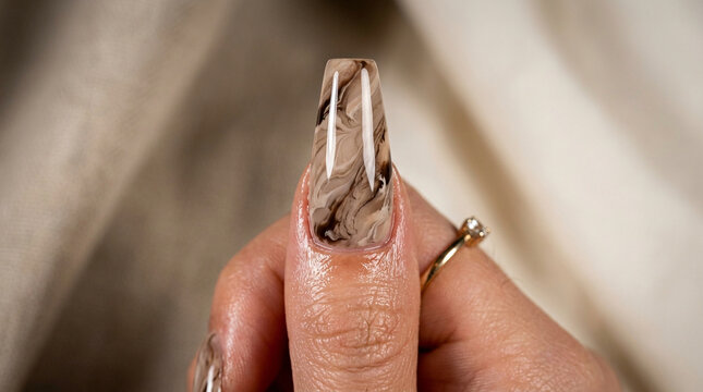Close up of manicured finger with brown marble pattern nail art design, manicure
