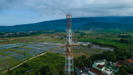 Obraz premium Aerial View of Telecommunications Tower in Rural Village with Farm Field, Cellular Infrastructure from Above