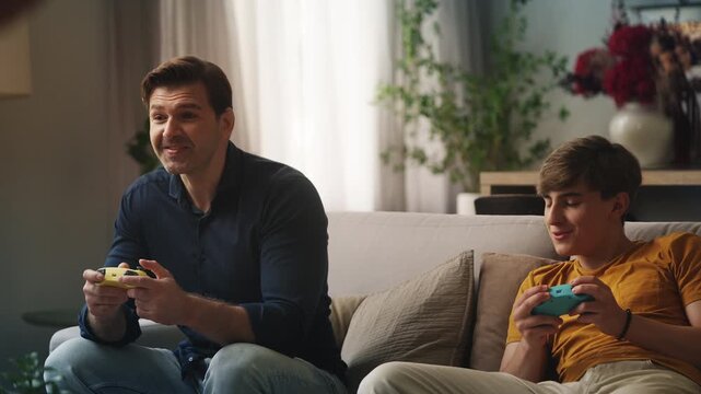 Adolescent boy and his father playing a video game, enjoying quality family time