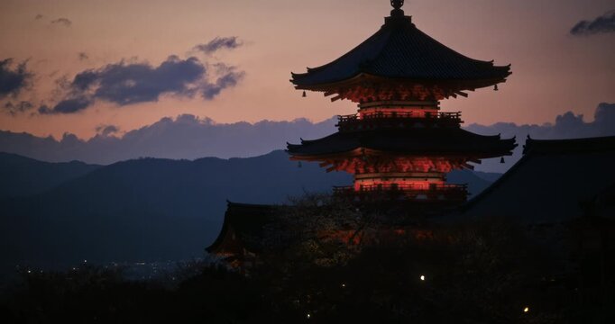 Glowing, silhouetted, ancient Japanese tower at dusk