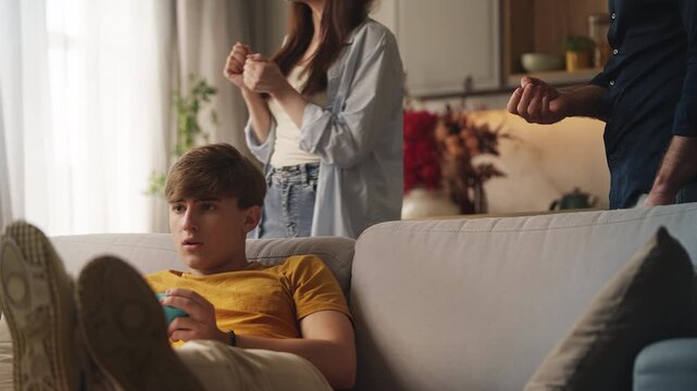 Parents reprimanding rebellious teenage son for excessive video gaming