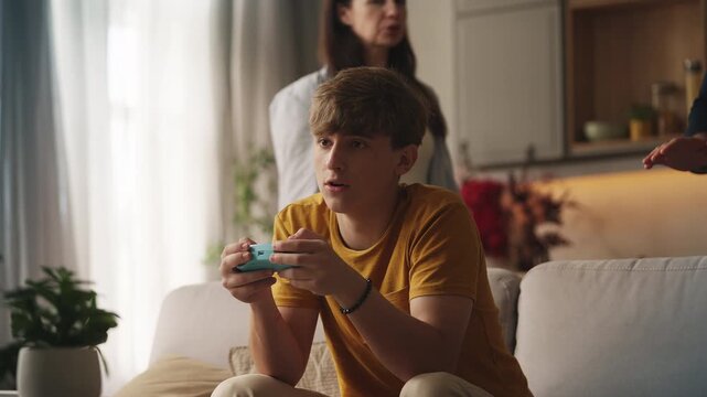 Displeased mother and father scolding teenage son for playing video games