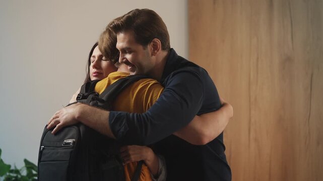 Upset parents hugging teenage son before he leaves home for college