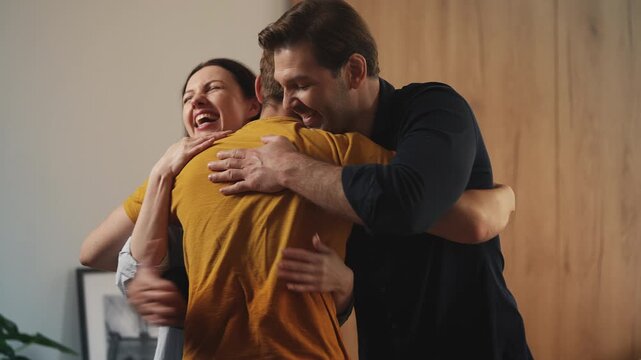 Teen boy hugging happy parents after returning home from college, family reunion