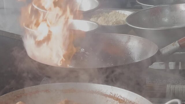 Dramatic wok tossing with big flames and fire explosion by chef cooking Asian stir fry on a hot gas stove, close up