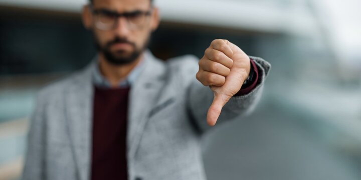 Businessman showing thumbs down gesture in corporate office interior