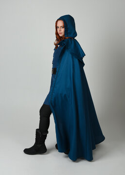 full length portrait of model wearing medieval fantasy warrior historical costume with blue hooded cloak. silhouette figure,  walking away in back view on studio background.