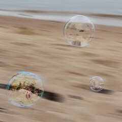 Soft bubbles drift above a sandy beach © WendlerCanning Photo