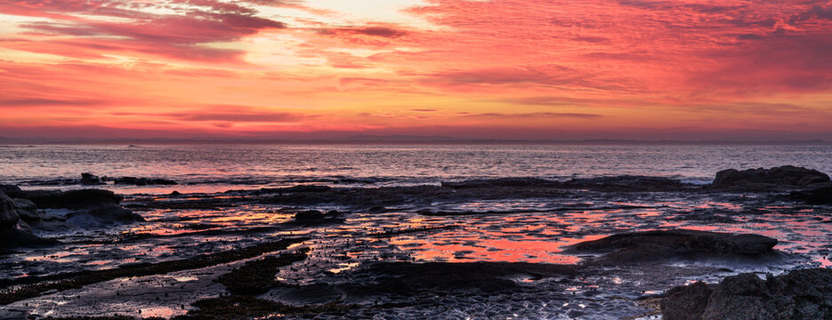 Crimson sky paints the ocean's edge with warm hues