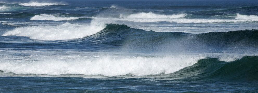 Powerful waves crash with white foam against deep blue ocean