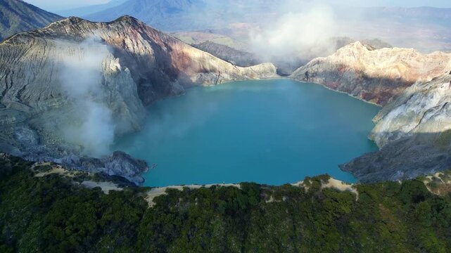 Spectacular drone flyover of iconic Mount Ijen volcanic crater &ndash; Amazing sulfuric steam rising into a warm golden hour morning sky, premium Indonesia travel and tourism advertising background