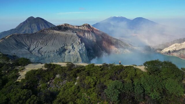 Cinematic aerial view of Mount Ijen volcano at sunrise &ndash; Breathtaking drone shot of the toxic turquoise crater lake and sulfur smoke clouds in East Java, Indonesia mountain landscape 4k