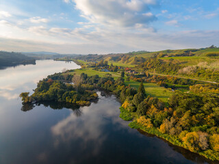 Naklejka premium Clouds reflected in the tranquil Waikato River, New Zealand, on a beautiful autumn day. Aerial view