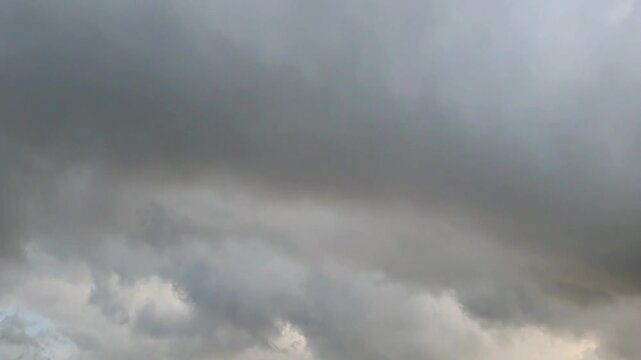 Dramatic time lapse of dark gray cumulus clouds rolling over a gloomy sky during a cloudy day, creating a moody and atmospheric scene.