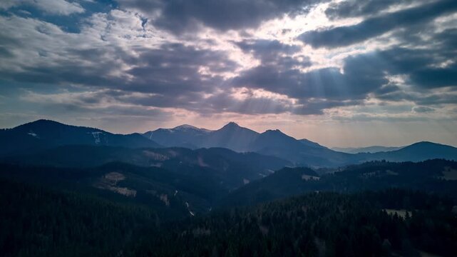 Aerial Hyperlapse of Sun Rays Breaking Through Clouds Over Mountain Forest
