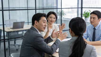 Obraz premium Colleagues participate in an animated conversation around a conference table in a bright office environment.