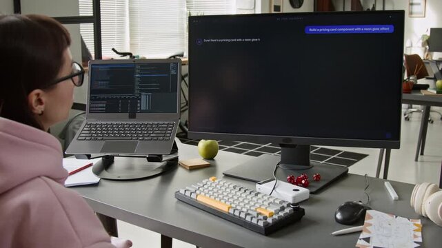 Medium dolly-in shot of female software engineer typing prompt for AI assistant, agent writing script according to request on black computer screen, demonstrating automation and enhanced productivity