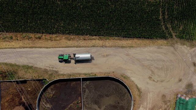 Tractor with tanker trailer transporting liquid manure fertilizer across farmland in Northern Italy.