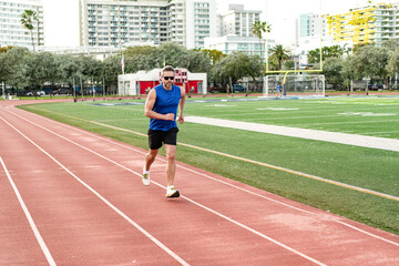 Obraz premium Man sportsman running for exercise. Man running at racetrack outdoor. Runner sprinted with incredible speed. Sport runner completing a marathon. Sport training. Fitness workout